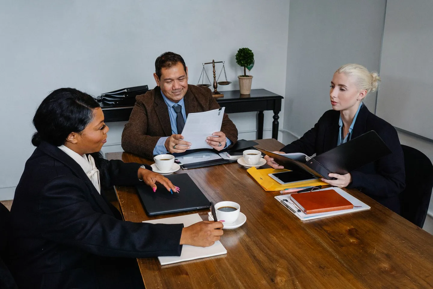 Three professionals discussing paperwork around a table